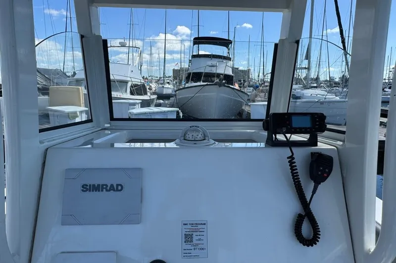 Slide: The Image of 2023 NauticStar 242L Offshore boat dashboard with Simrad navigation system at marina. - 35