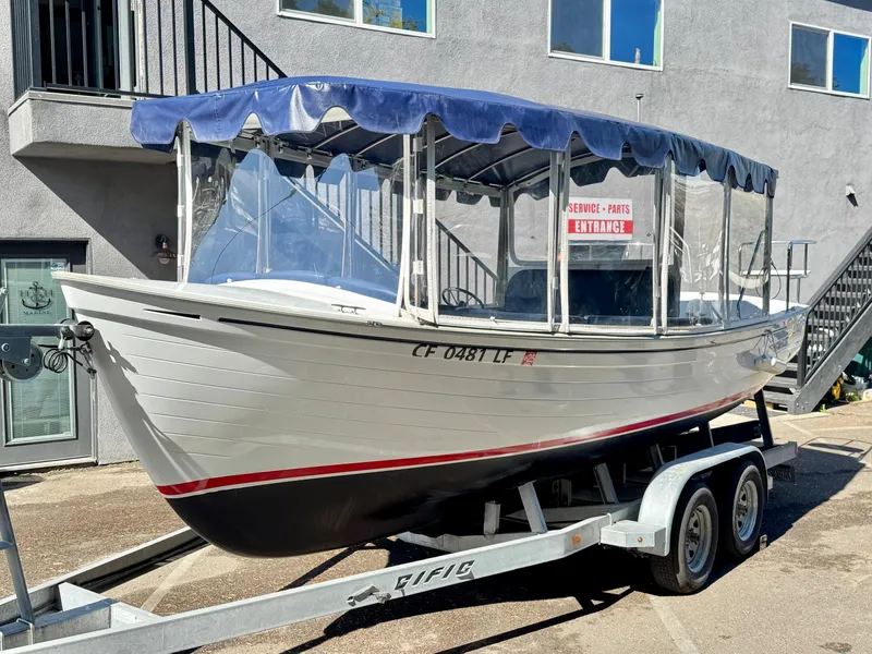 Slide: The Image of 2022 Duffy Sun Cruiser boat on trailer with blue canopy, parked near building. - 0