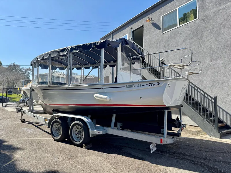 Slide: The Image of 2022 Duffy Sun Cruiser boat on trailer, parked near a building. - 2