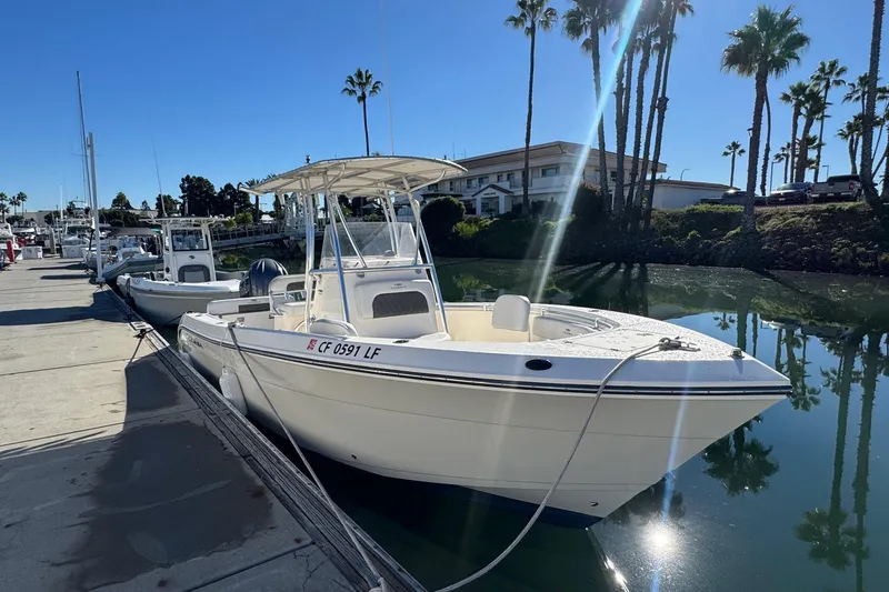 Slide: The Image of 2022 Cobia 237 Center Console boat docked in sunny marina setting. - 10