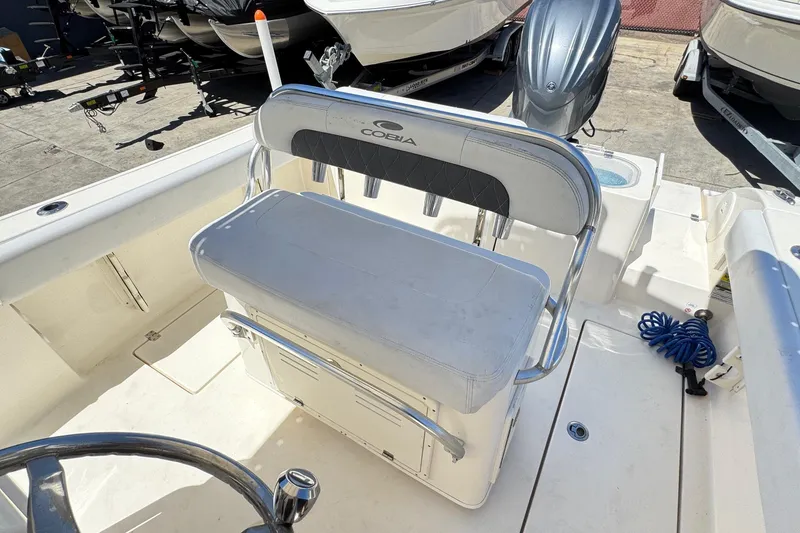 Slide: The Image of 2022 Cobia 237 Center Console boat interior with seating and motor, docked outdoors. - 19