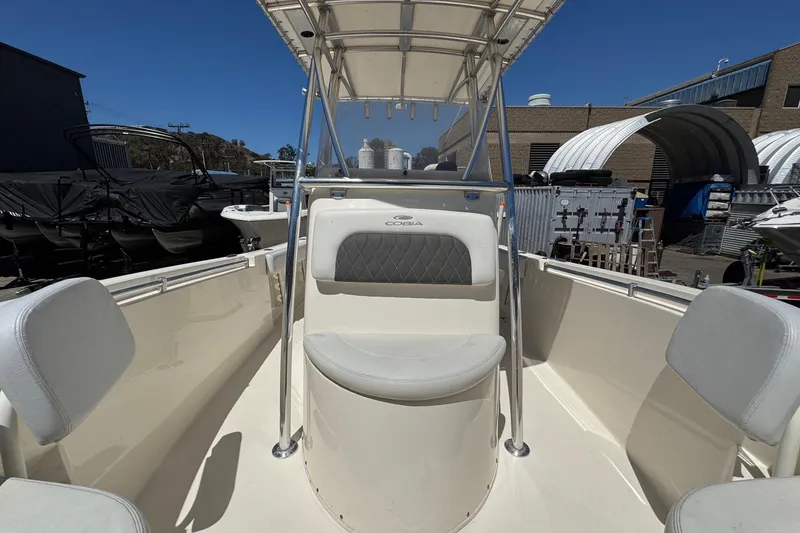 Slide: The Image of 2022 Cobia 237 Center Console boat interior with seating and canopy, docked outdoors. - 29