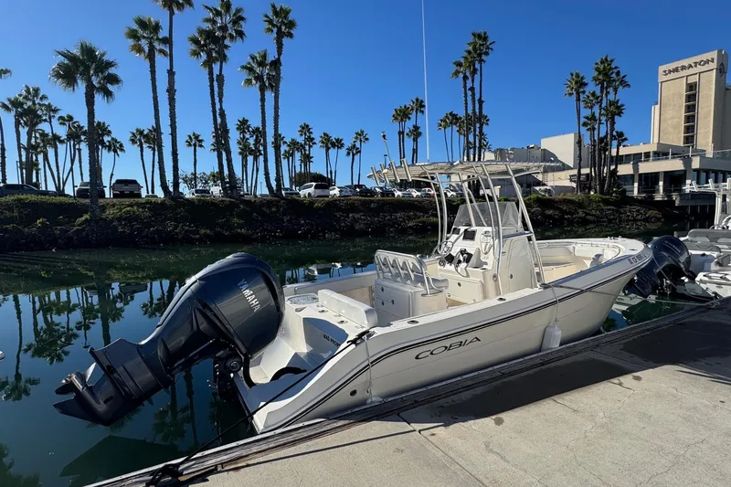 Slide: The Image of 2022 Cobia 237 Center Console boat docked near palm trees and hotel. - 3