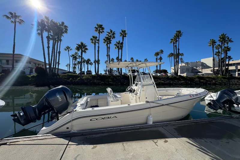 Slide: The Image of 2022 Cobia 237 Center Console boat docked under clear blue sky. - 6