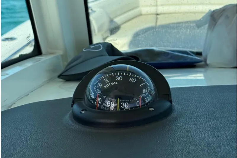 Slide: The Image of Compass on 2020 Boston Whaler 330 Outrage dashboard, overlooking calm blue waters. - 14