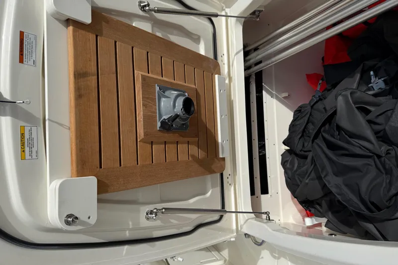 Slide: The Image of 2020 Boston Whaler 330 Outrage storage compartment with wooden panel and gear inside. - 25
