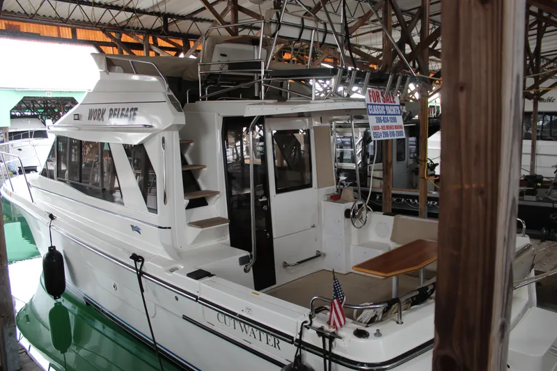 Slide: The Image of 2016 Cutwater 30 Command Bridge yacht for sale in marina, featuring spacious deck and seating. - 1