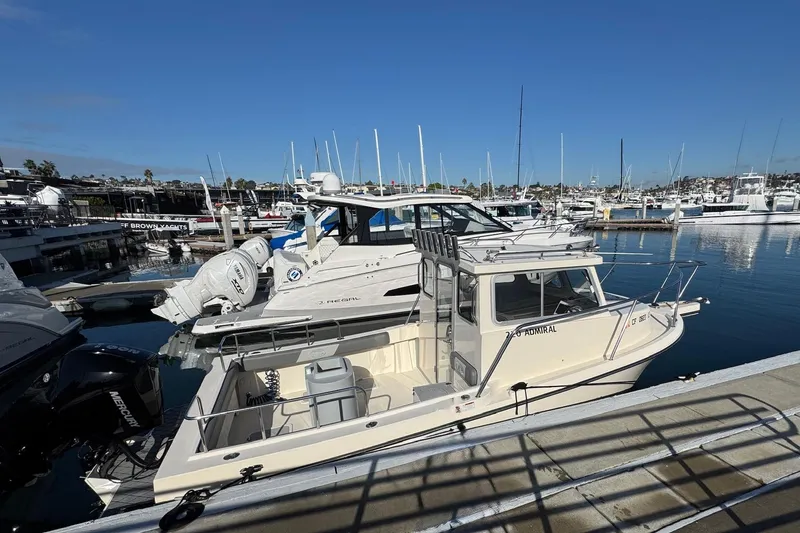 Slide: The Image of 2023 Defiance Admiral 220 EX boat docked at a marina under clear blue skies. - 10