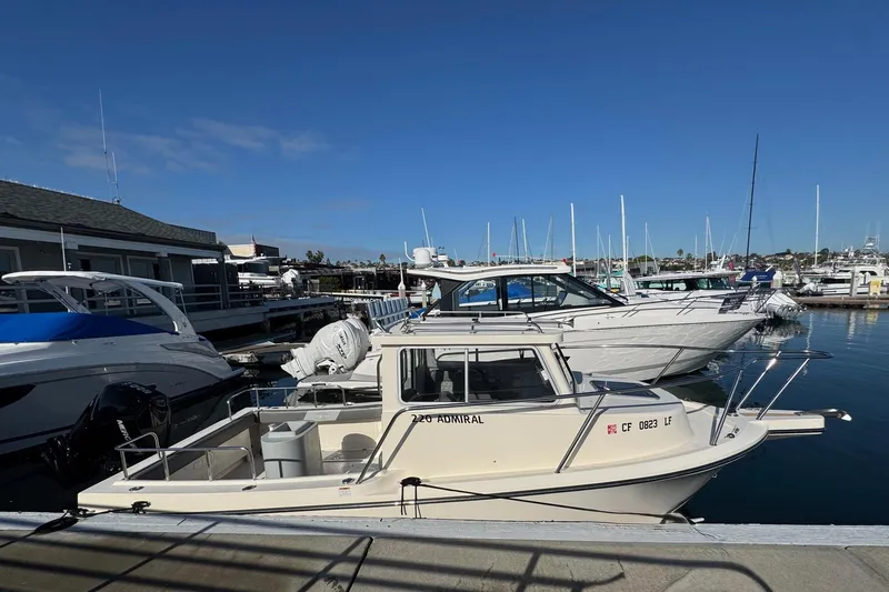 Slide: The Image of 2023 Defiance Admiral 220 EX boat docked at a marina under clear blue skies. - 7