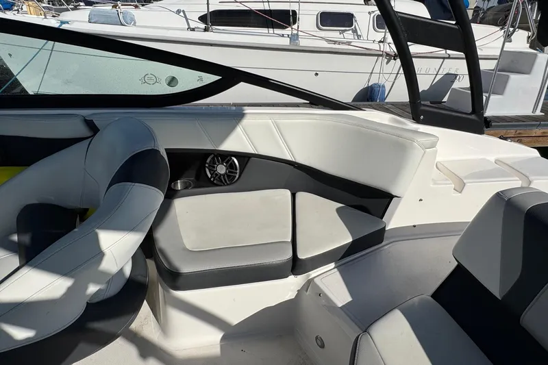 Slide: The Image of 2024 Regal 21 OBX boat interior with cushioned seating and speaker, docked at marina. - 16