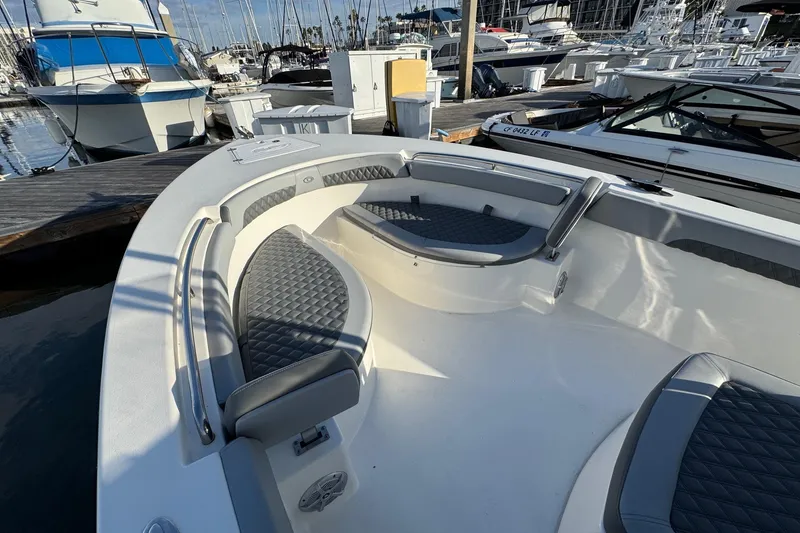 Slide: The Image of 2025 Defiance Catalina 240 boat interior with cushioned seating at a marina. - 15