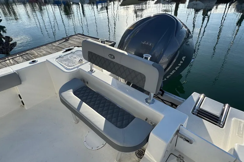 Slide: The Image of 2025 Defiance Catalina 240 boat interior with Yamaha engine, featuring cushioned seating and dockside view. - 33