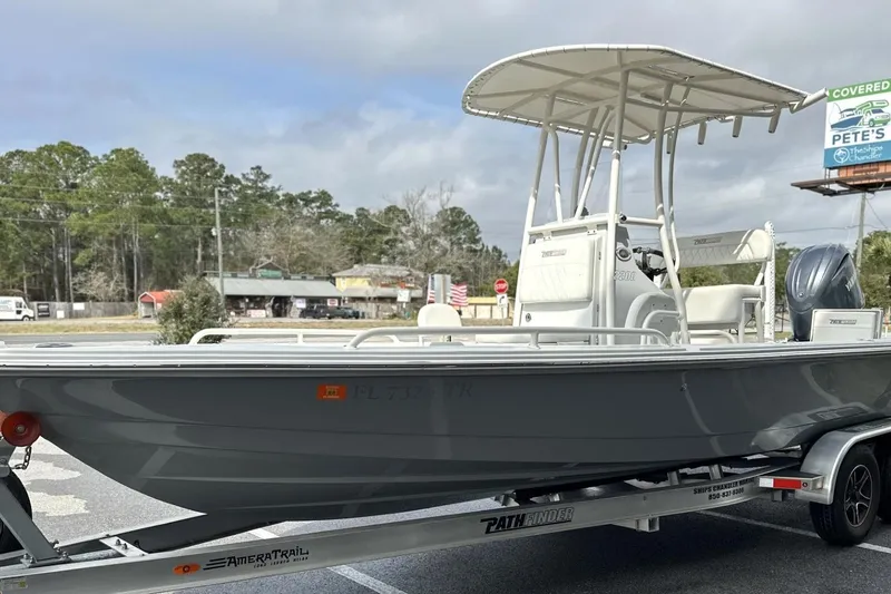 Slide: The Image of 2024 Pathfinder 2200 TRS boat on trailer, parked outdoors under cloudy sky. - 12