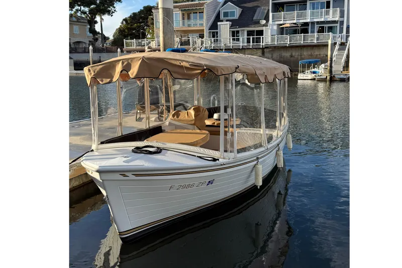 Slide: The Image of 2022 Duffy 16 electric boat docked in a marina with waterfront homes. - 1