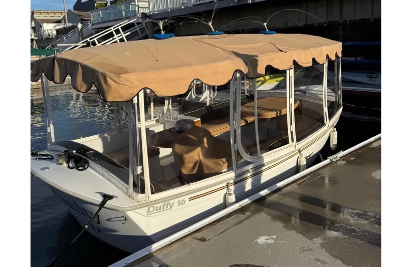 Slide: The Image of Electric Duffy 16 boat, 2022 model, docked with beige canopy and clear windows. - 3
