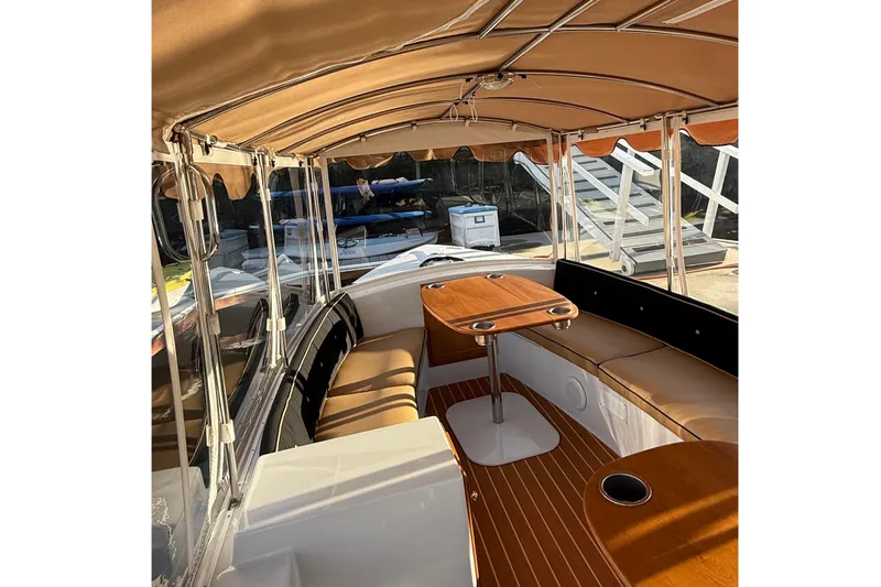 Slide: The Image of Interior of 2022 Duffy 16 boat with tan canopy and wooden table. - 6