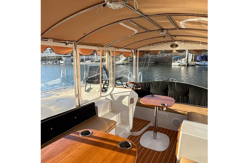 Slide: The Image of Interior of a 2022 Duffy 16 boat with seating and steering wheel, docked by the water. - 7