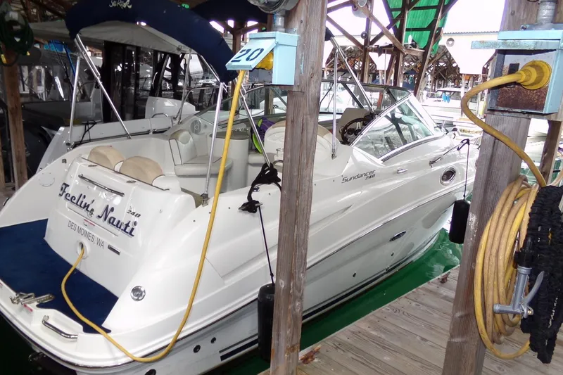 Slide: The Image of 2009 Searay Sundancer boat docked, featuring white exterior and blue accents. - 2