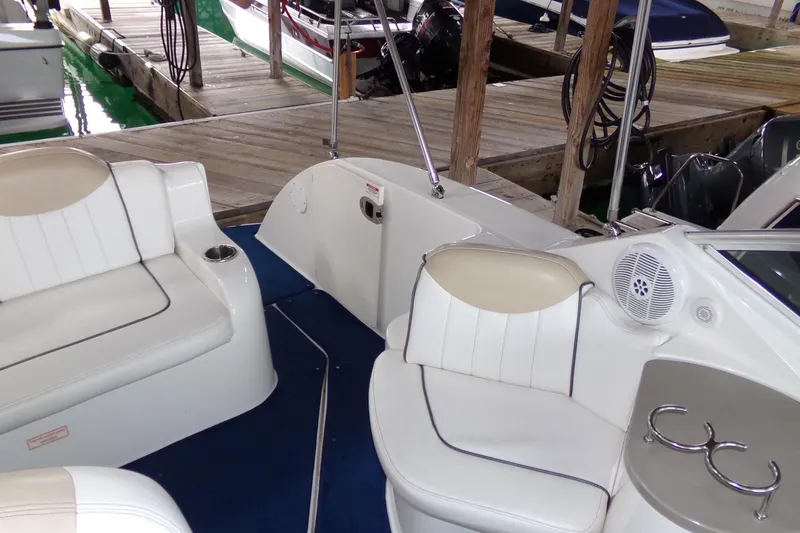 Slide: The Image of 2009 Searay Sundancer boat interior with white seating and blue carpet at a dock. - 9