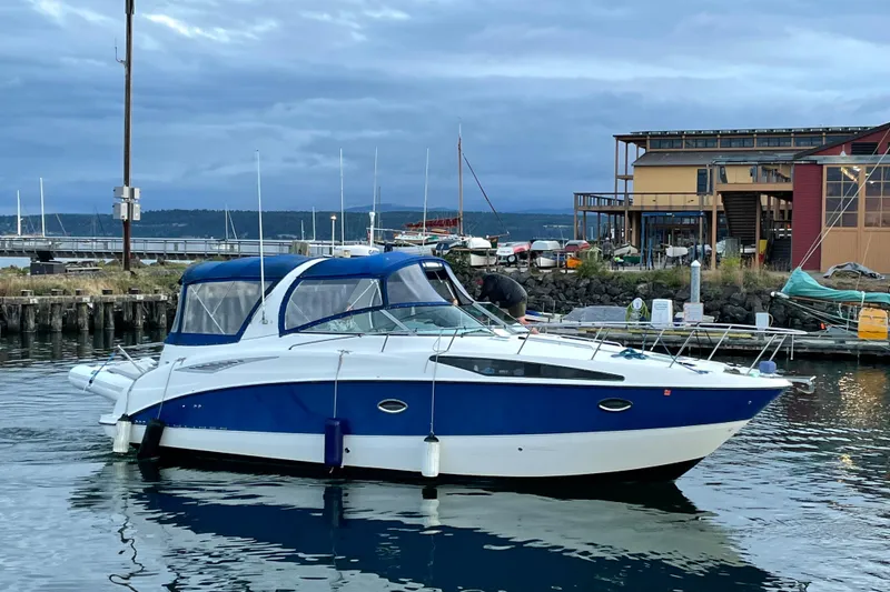 The Image of 2006 Bayliner 325 boat docked at a marina, featuring a sleek blue and white design. - 0
