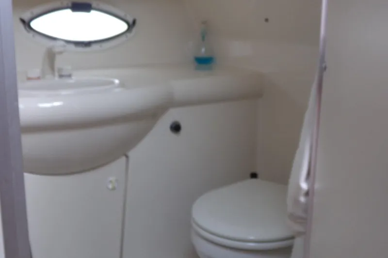 Slide: The Image of 2006 Bayliner 325 boat bathroom with sink, toilet, and porthole window. - 14
