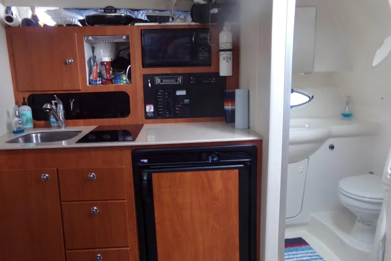 Slide: The Image of 2006 Bayliner 325 interior with kitchenette and bathroom, featuring wood cabinetry and modern amenities. - 15