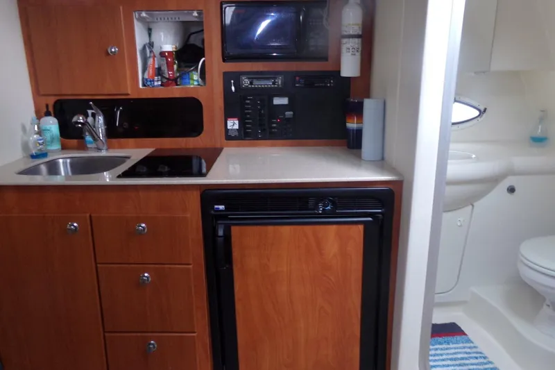 Slide: The Image of 2006 Bayliner 325 yacht interior with kitchenette, sink, stove, and bathroom. - 16