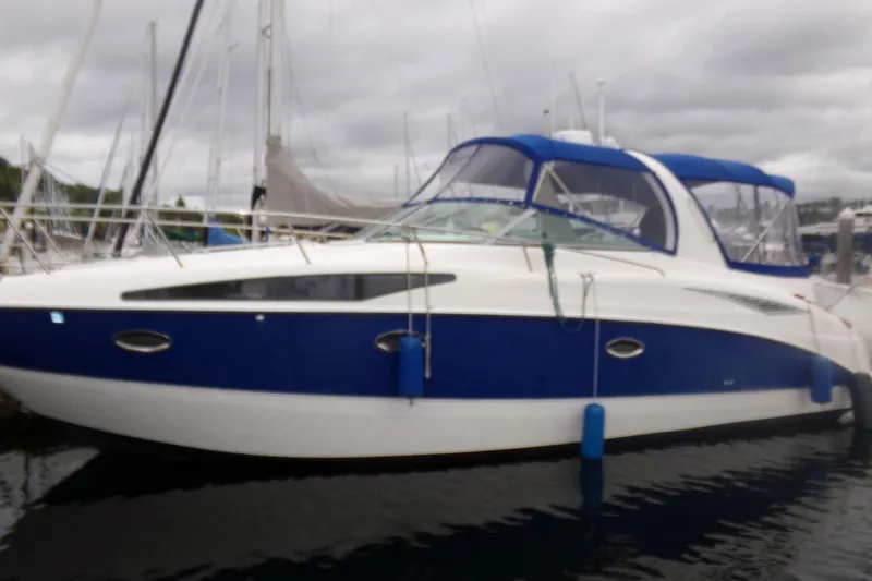 Slide: The Image of 2006 Bayliner 325 boat docked, featuring blue and white exterior with canopy. - 2