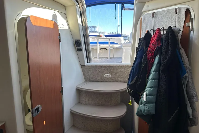 Slide: The Image of Interior view of a 2006 Bayliner 325 boat with coats hanging and steps leading outside. - 22