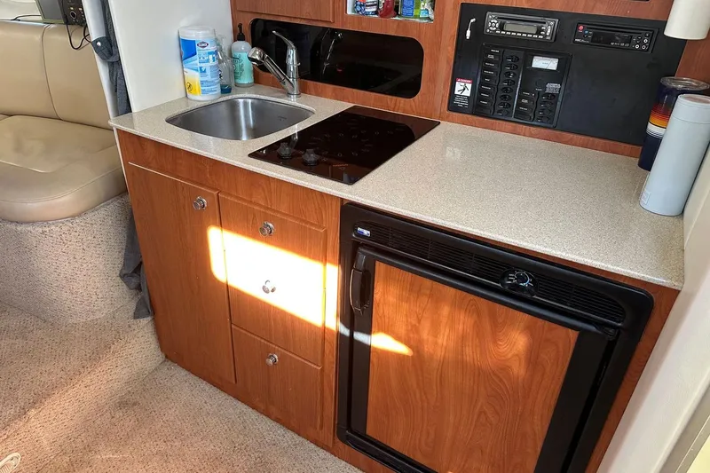Slide: The Image of Compact kitchen area in a 2006 Bayliner 325 boat with sink, stove, and fridge. - 23