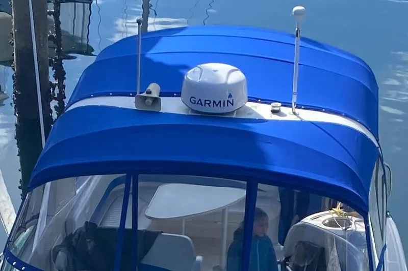 Slide: The Image of Blue canopy on 2006 Bayliner 325 boat with Garmin equipment, docked on calm water. - 28