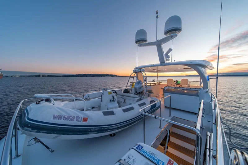 Slide: The Image of 2013 Ocean Alexander 72 Pilothouse yacht at sunset, featuring a spacious deck and tender. - 12