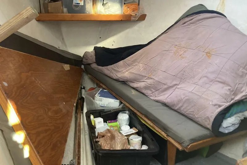 Slide: The Image of Cozy interior of a 1986 BGM Custom boat with a makeshift bed and storage. - 19