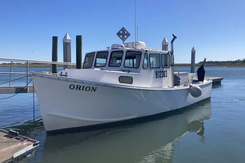 Slide: The Image of White 1986 BGM Custom boat "Orion" docked in calm waters under clear blue sky. - 2