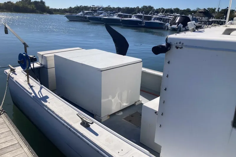 Slide: The Image of 1986 BGM Custom boat docked, featuring storage compartments and marina view. - 15