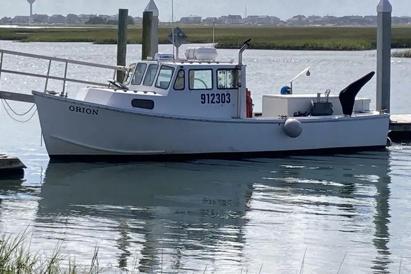Slide: The Image of White BGM Custom 1986 boat named Orion docked in a serene harbor. - 34