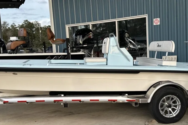 Slide: The Image of 2024 Maverick 18 HPX-V boat on trailer, parked outside a blue building. - 16