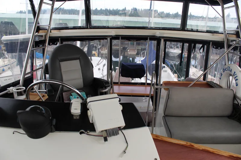 Slide: The Image of 1987 Carver 36 Aft Cabin Motor Yacht helm with marina view, featuring steering wheel and seating. - 11