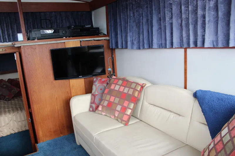 Slide: The Image of Interior of 1987 Carver 36 Aft Cabin Motor Yacht with sofa, TV, and decorative pillows. - 16
