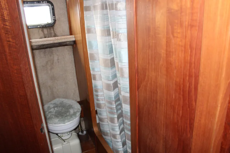 Slide: The Image of 1987 Carver 36 Aft Cabin Motor Yacht bathroom with wooden paneling and shower curtain. - 27