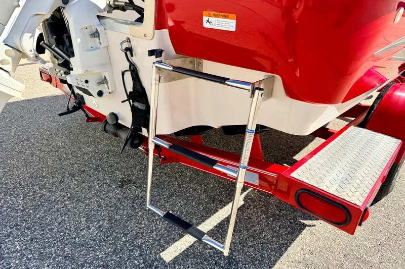 Slide: The Image of 2003 Glastron/Carlson GX180 boat with red hull and foldable ladder on trailer. - 11