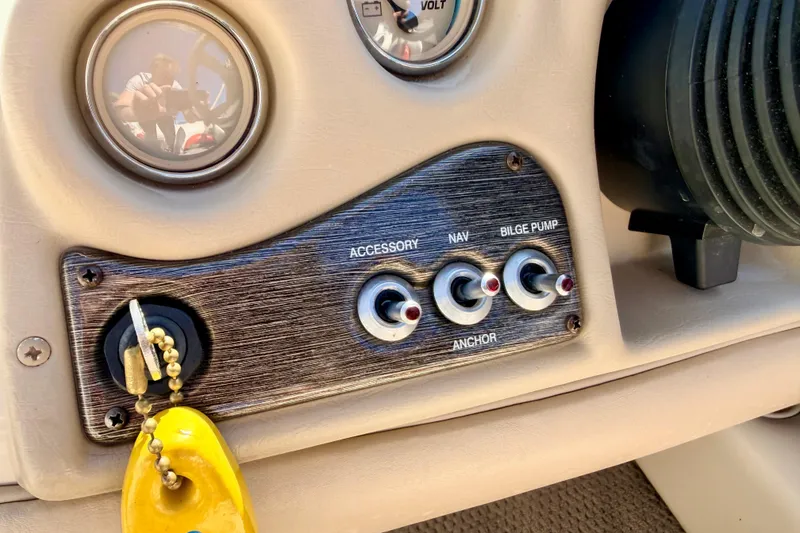 Slide: The Image of 2003 Glastron/Carlson GX180 boat dashboard with switches and keychain. - 32