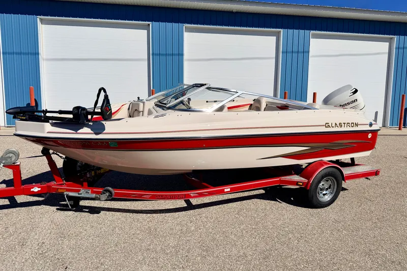 Slide: The Image of 2003 Glastron/Carlson GX180 boat on red trailer, parked near blue building. - 58