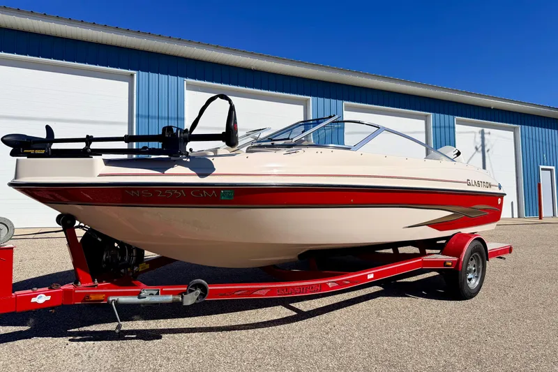 Slide: The Image of 2003 Glastron/Carlson GX180 boat on red trailer, parked near blue building. - 60