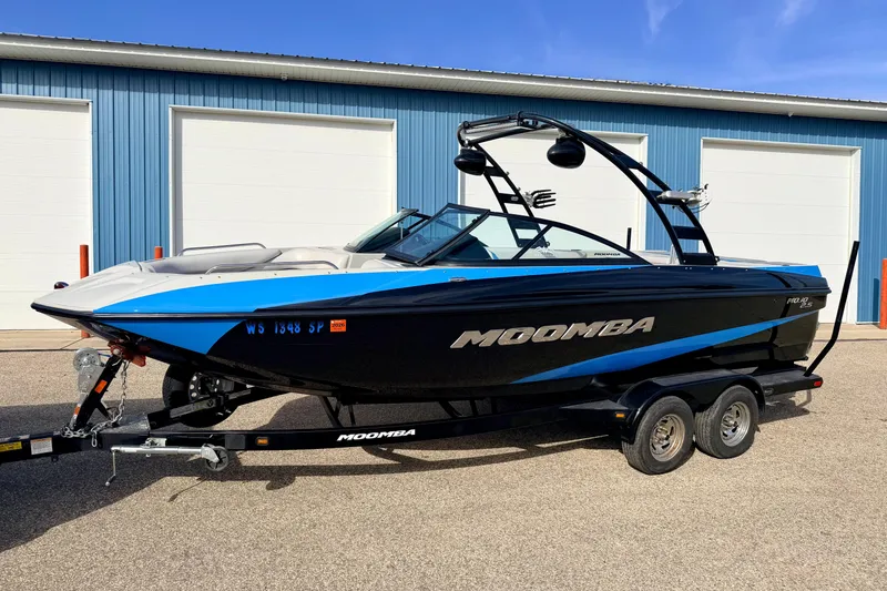 Slide: The Image of 2012 Moomba Mojo 2.5 boat on trailer, parked near blue building. - 2