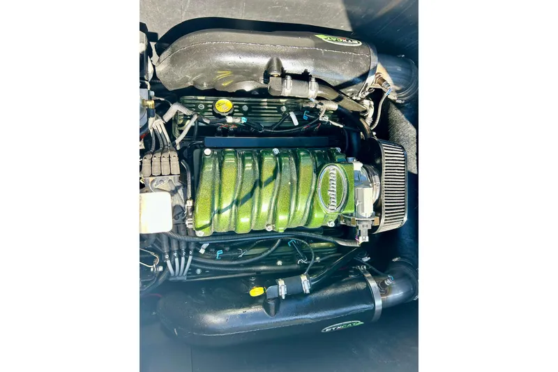 Slide: The Image of 2012 Moomba Mojo 2.5 engine with green metallic cover and intricate wiring. - 53