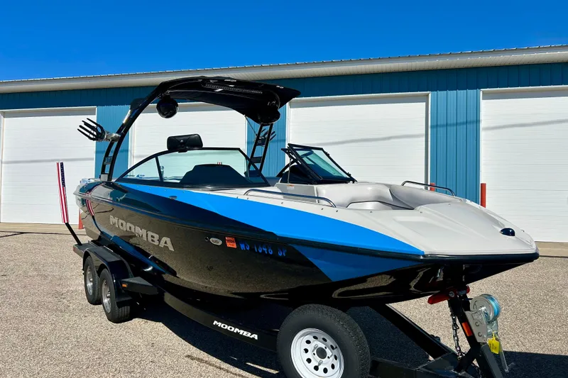 Slide: The Image of 2012 Moomba Mojo 2.5 boat with American flag detail, parked outside blue building. - 72