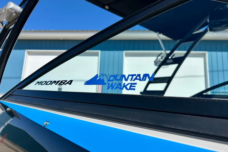 Slide: The Image of 2012 Moomba Mojo 2.5 boat on trailer, parked outdoors under clear blue sky. - 74