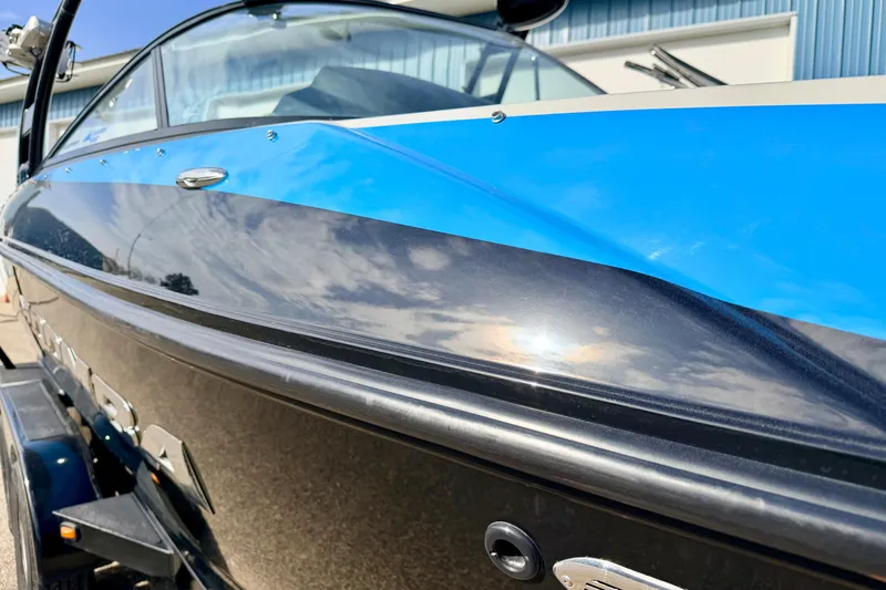 Slide: The Image of 2012 Moomba Mojo 2.5 boat with sleek blue and black design, parked outdoors. - 8