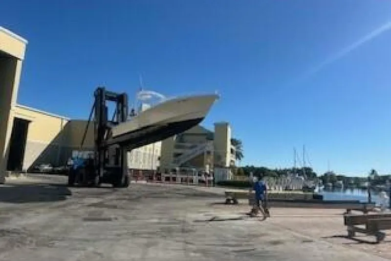 Slide: The Image of Forklift lifting 2019 OceanPro 35 boat near marina under clear blue sky. - 14